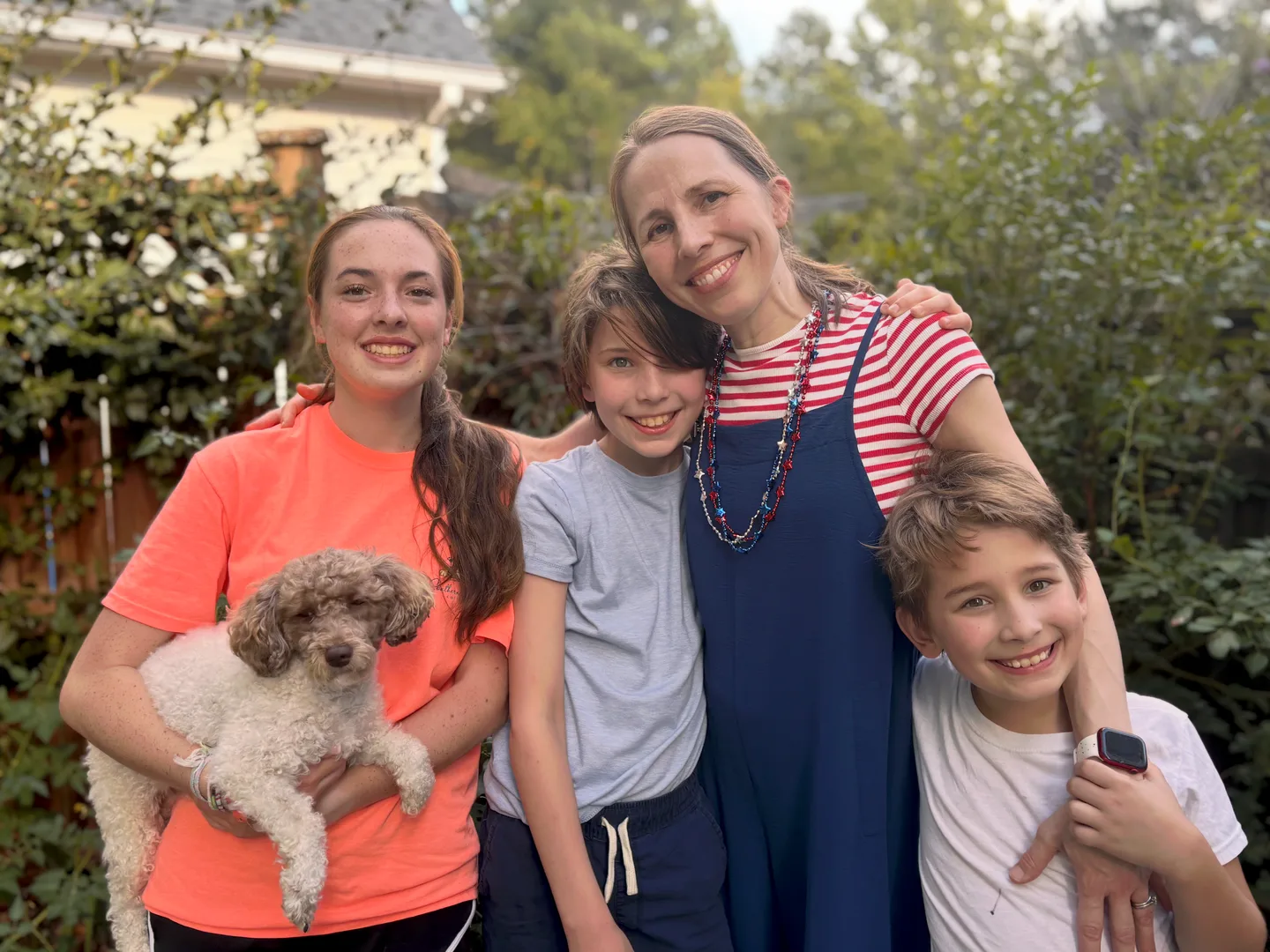 Angela outdoors with her three children and the family dog